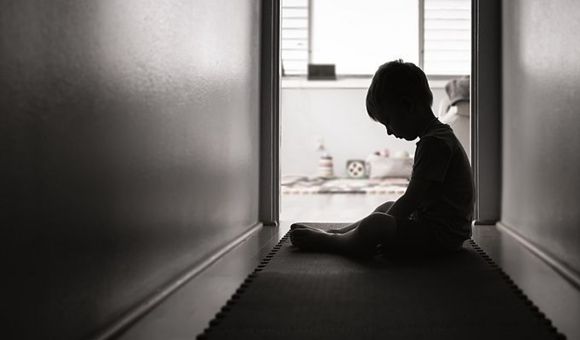 Un niño sentado en el suelo cabizbajo